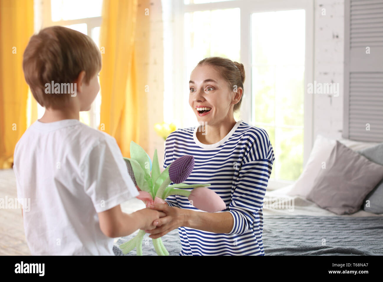 Mother receiving flowers from her cute little son at home Stock Photo