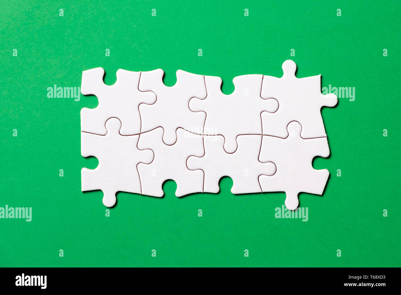 Eight pieces white jigsaw puzzle on green background for business presentation Stock Photo