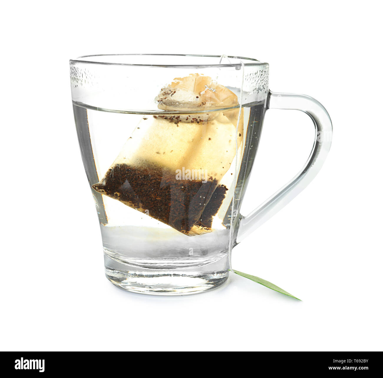 Brewing of hot beverage in glass cup using teabag, on white background
