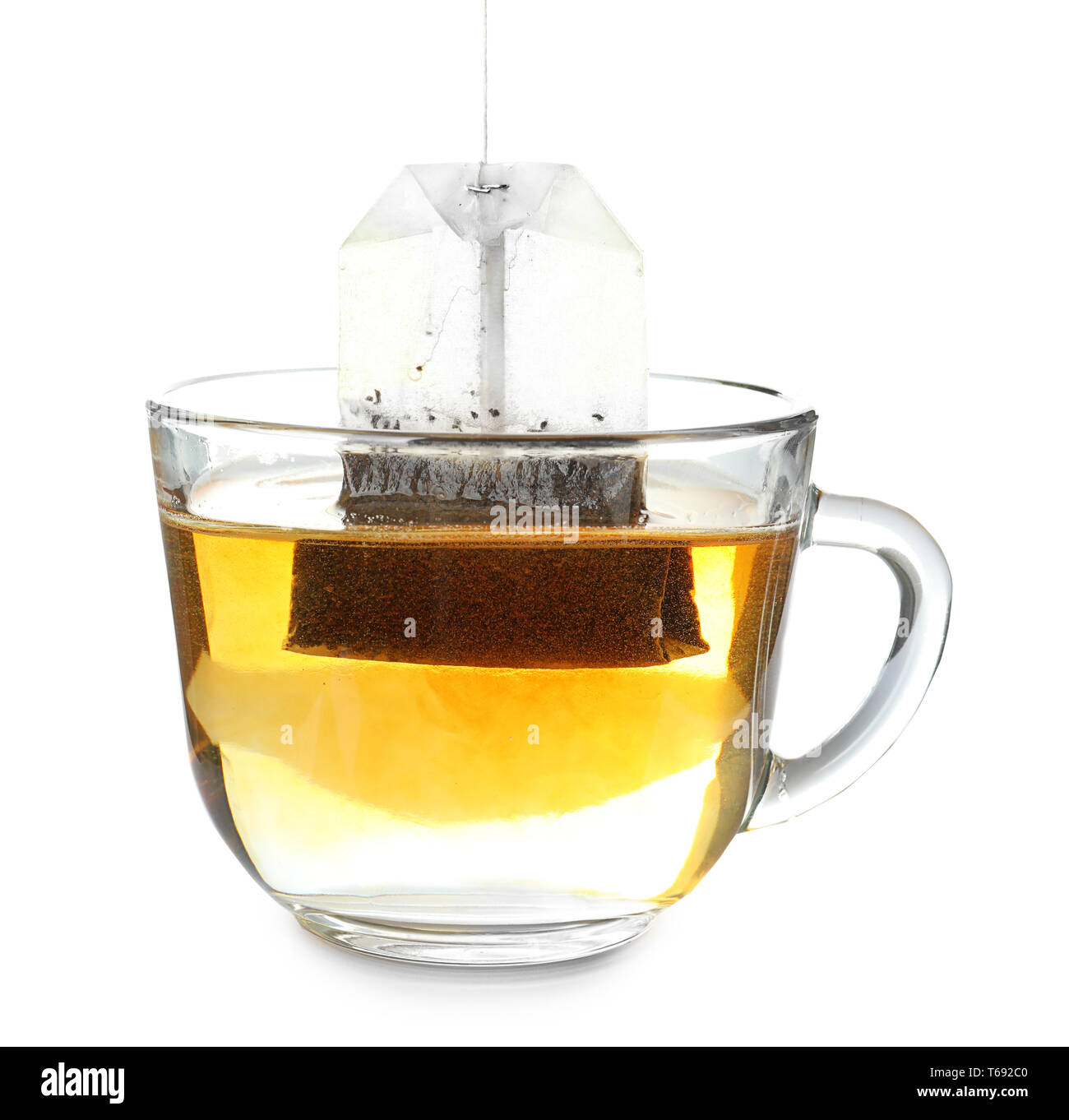 Brewing of hot beverage in glass cup using teabag, on white background