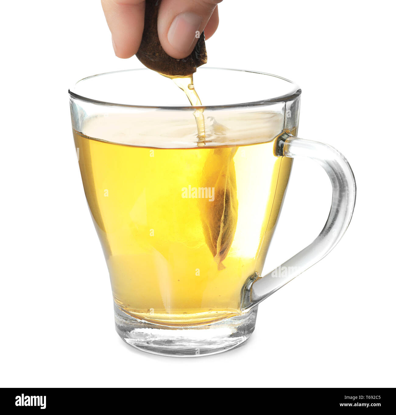 Brewing of hot beverage in glass cup using teabag, on white background