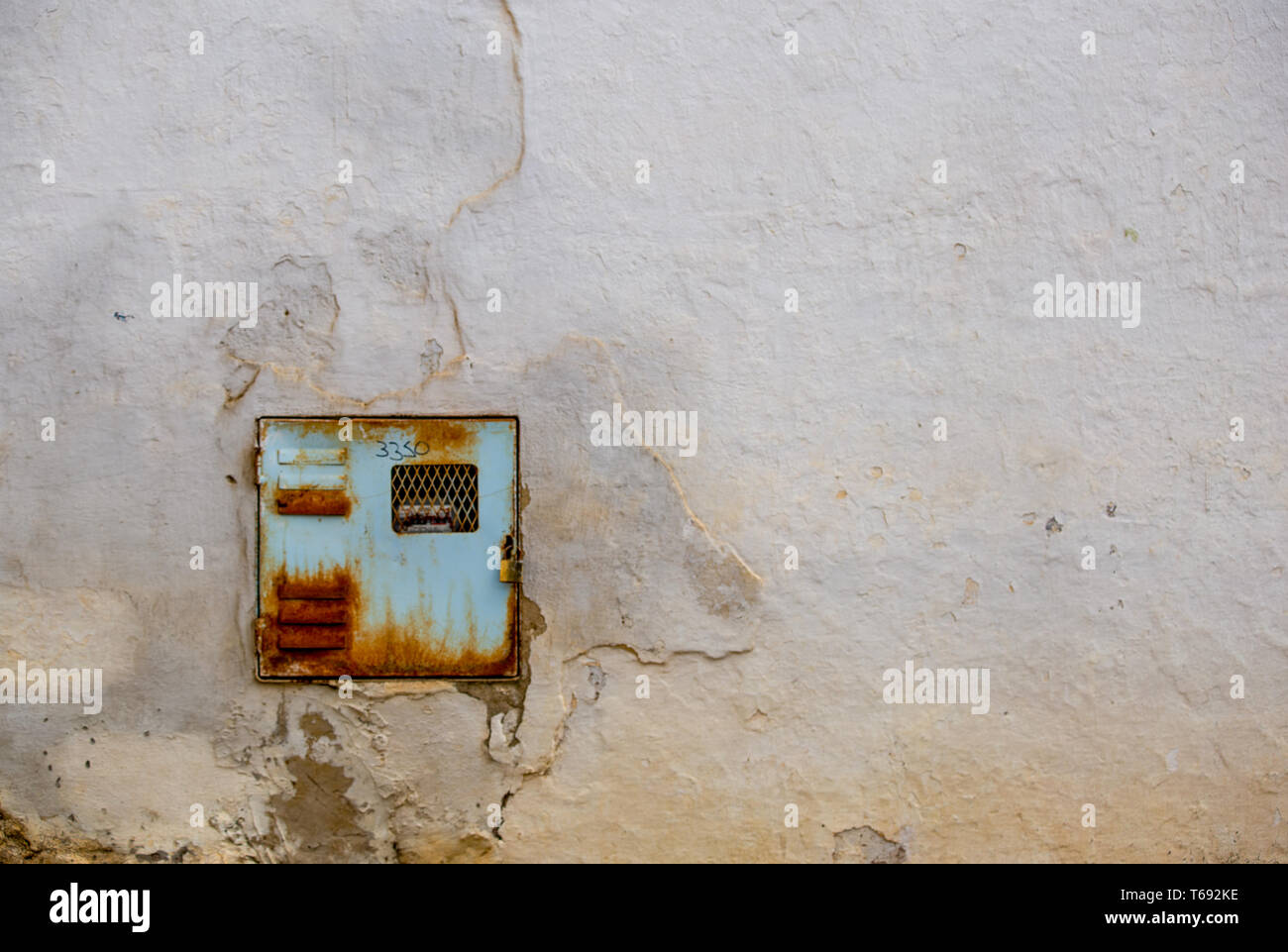 An old and rusty electricity meter fits perfectly in a very deteriorated wall of one street of the colonial town of Villa de Leyva, Colombia. Stock Photo