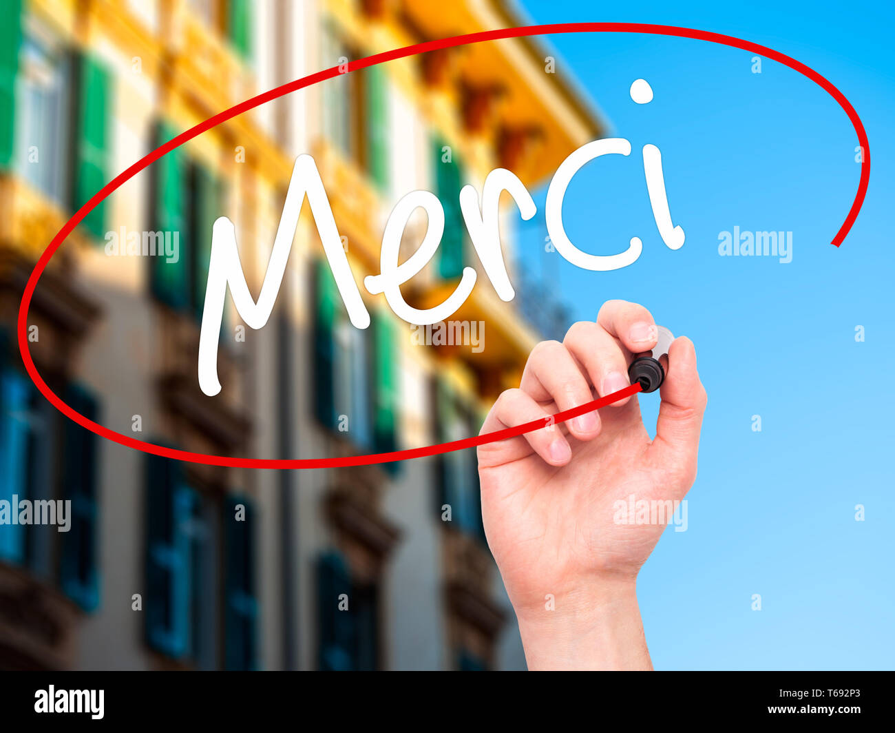 Man Hand writing Merci  (Thank You In French) with black marker on visual screen. Stock Photo