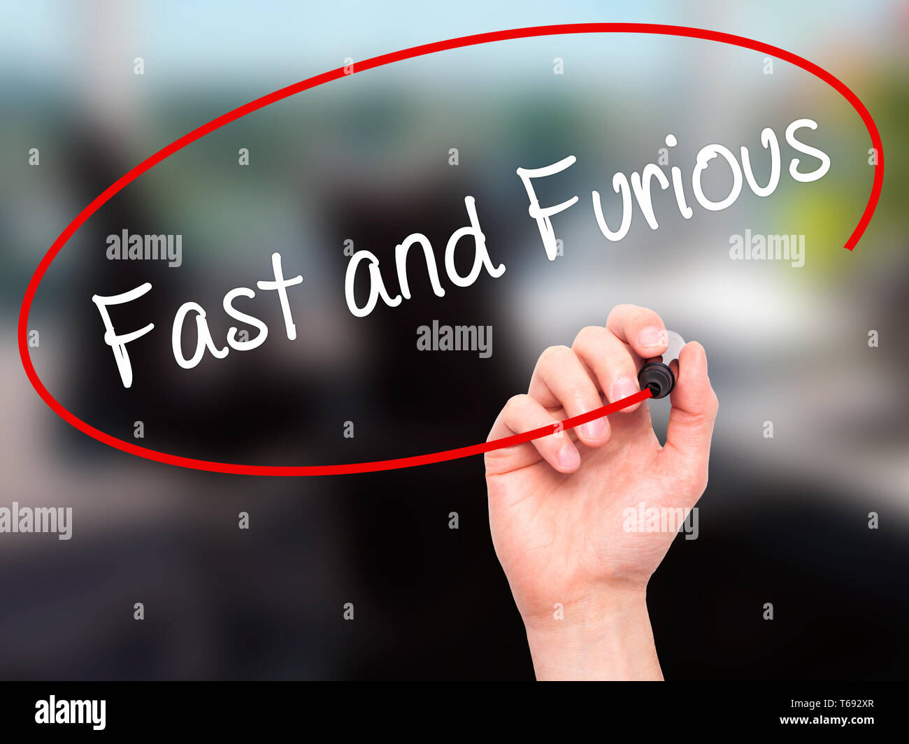 Man Hand writing Fast and Furious with black marker on visual screen Stock Photo