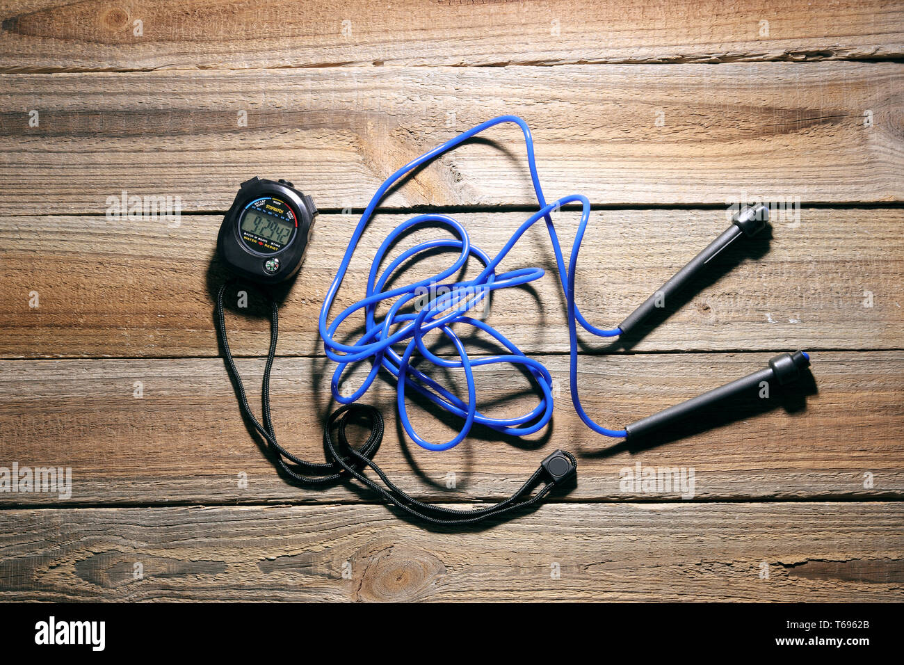 Stopwatch and Skipping Rope on Wooden Background Stock Photo