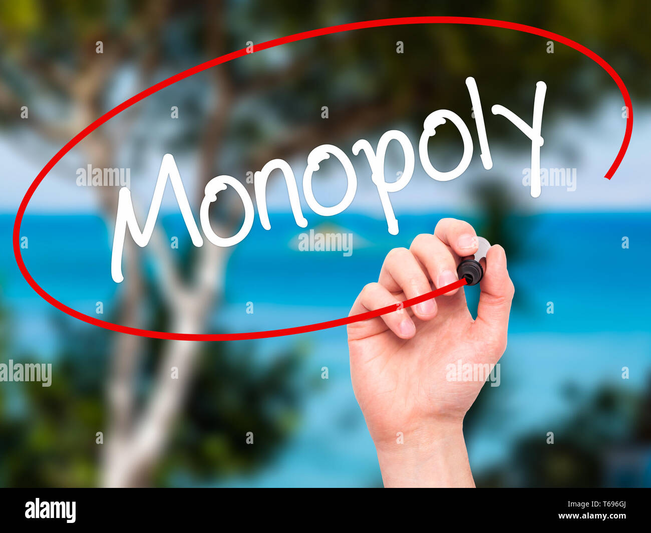 Man Hand writing Monopoly with black marker on visual screen. Stock Photo