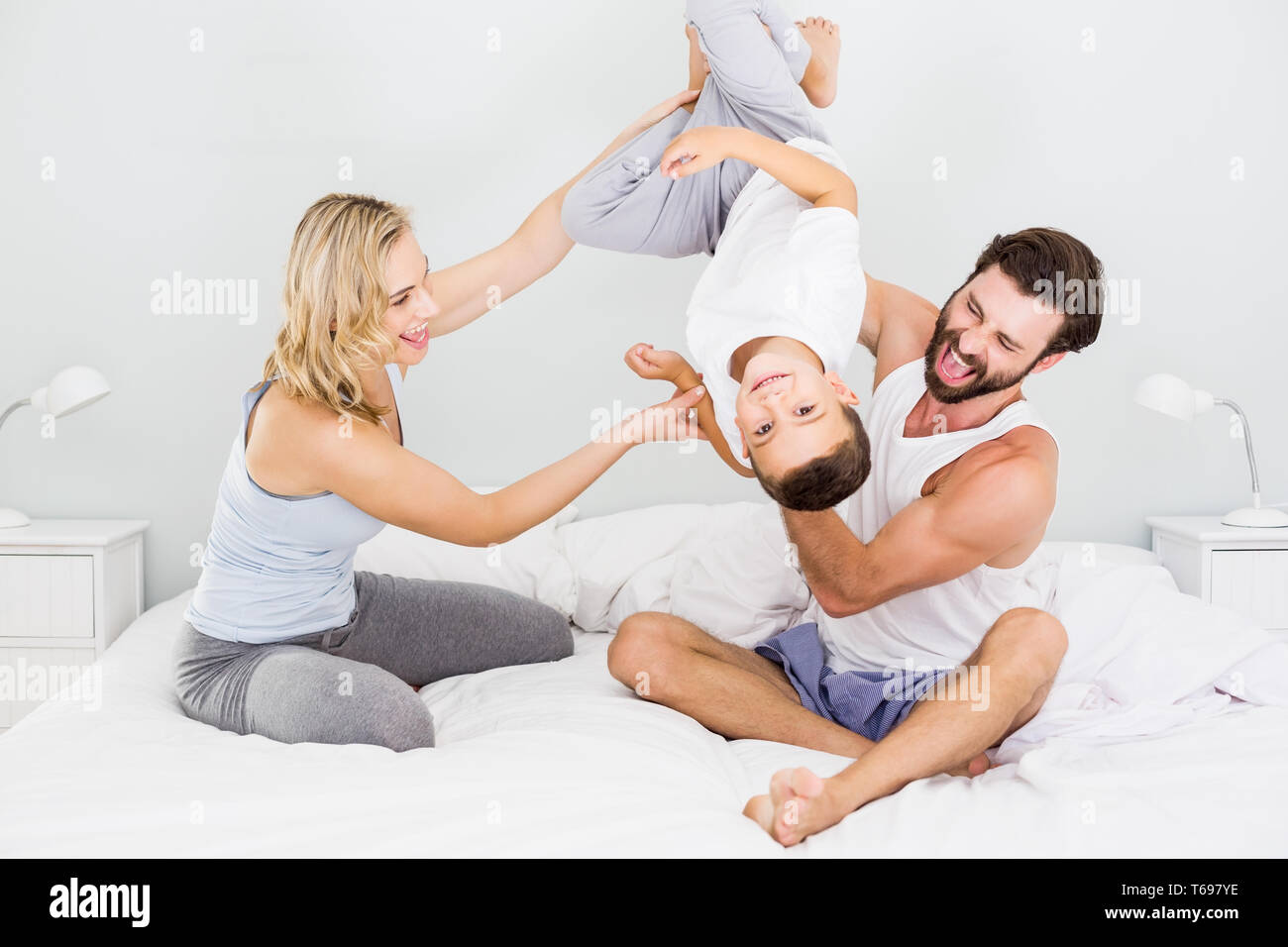 Parents and son sitting on bed and having fun in bedroom Stock Photo ...