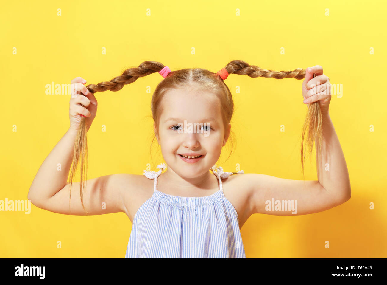Closeup portrait of a cheerful little girl on a yellow background. The ...