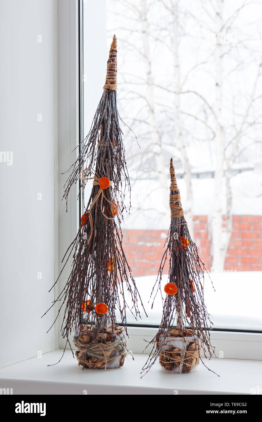 Abstract Christmas trees from natural materials standing on the windowsill. Stock Photo