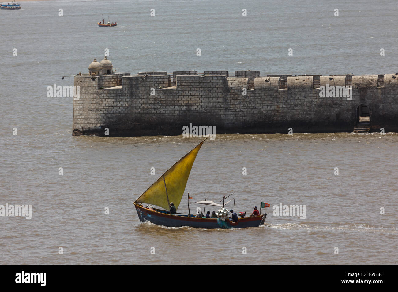 Traditional sailboat leaving harbor in Diu, India with passengers in rear Stock Photo