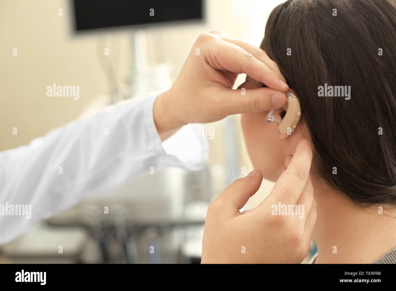Otolaryngologist putting hearing aid in woman's ear indoors Stock Photo ...