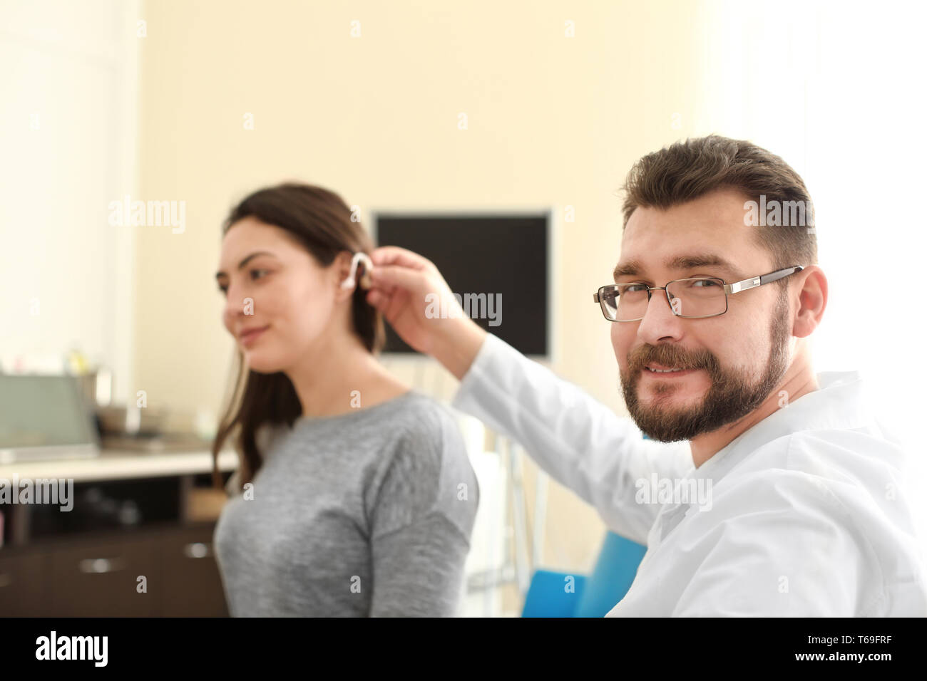 Otolaryngologist putting hearing aid in woman's ear indoors Stock Photo ...