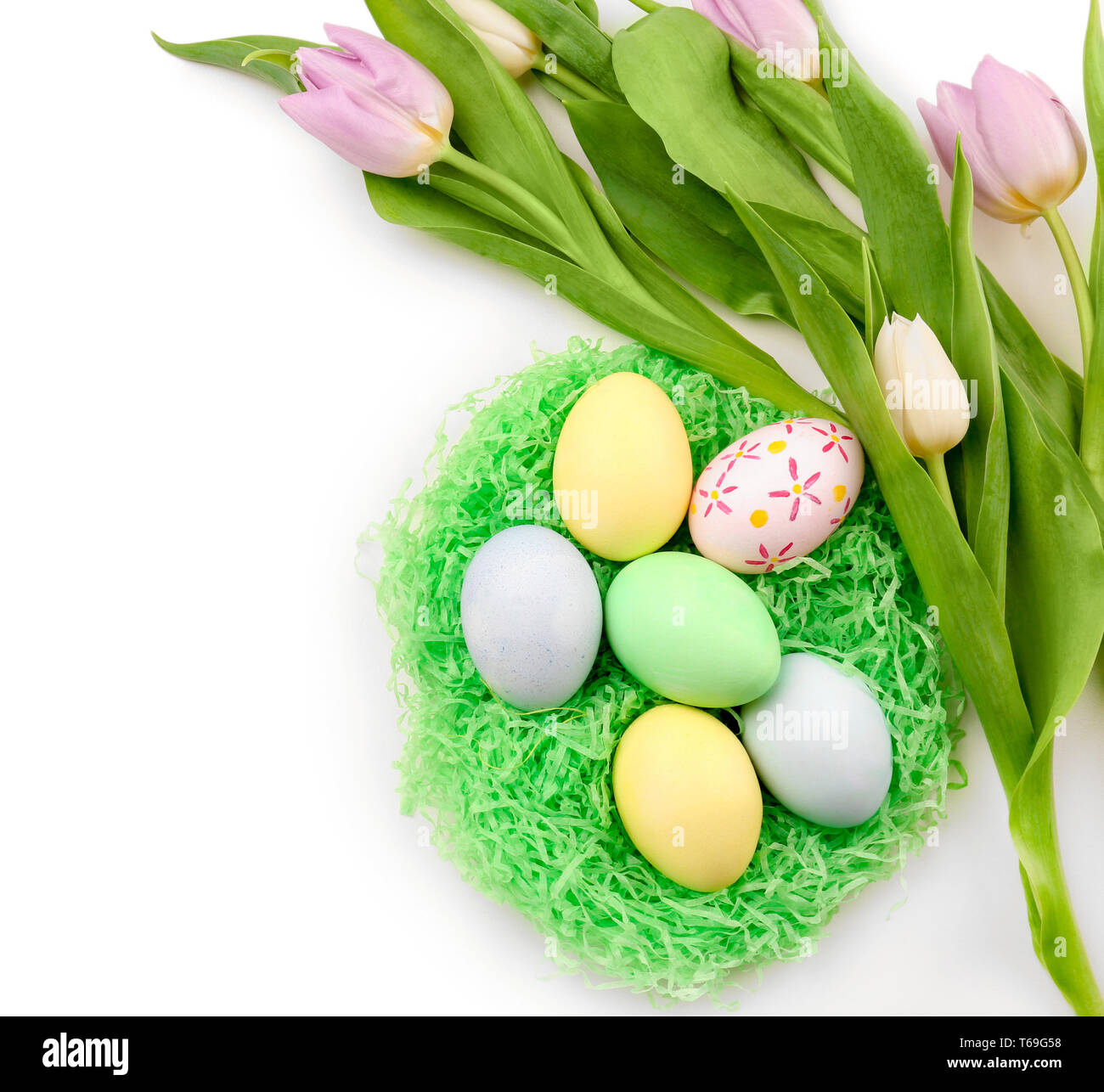Decorative nest with dyed Easter eggs and spring flowers on white ...