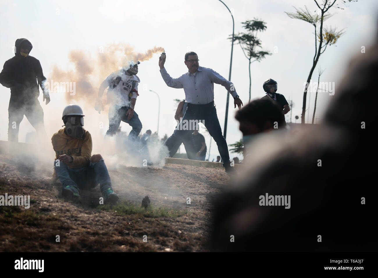 Caracas, Venezuela. 30th Apr, 2019. A man in civilian clothes throws a tear gas grenade around the self-proclaimed interim president Guaido near the air base La Carlota during a mission with soldiers. 'As interim president of Venezuela, as legitimate supreme commander of the armed forces, I call on all soldiers to join us,' says the opposition leader on a highway. Credit: Rafael Hernandez/dpa/Alamy Live News Stock Photo