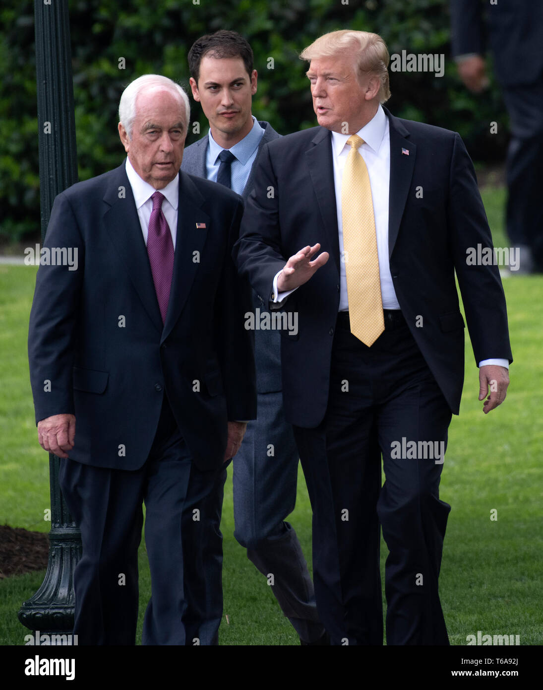 Washington, United States Of America. 30th Apr, 2019. United States President Donald J. Trump, right, walks with Roger Penske, Team Penske's Chairman and Founder, left, and the 2018 NASCAR Cup Series Champion, Joey Logano, center, as he prepares to welcome them to the South Lawn of the White House in Washington, DC on April 30, 2019. Credit: Ron Sachs/CNP | usage worldwide Credit: dpa/Alamy Live News Stock Photo