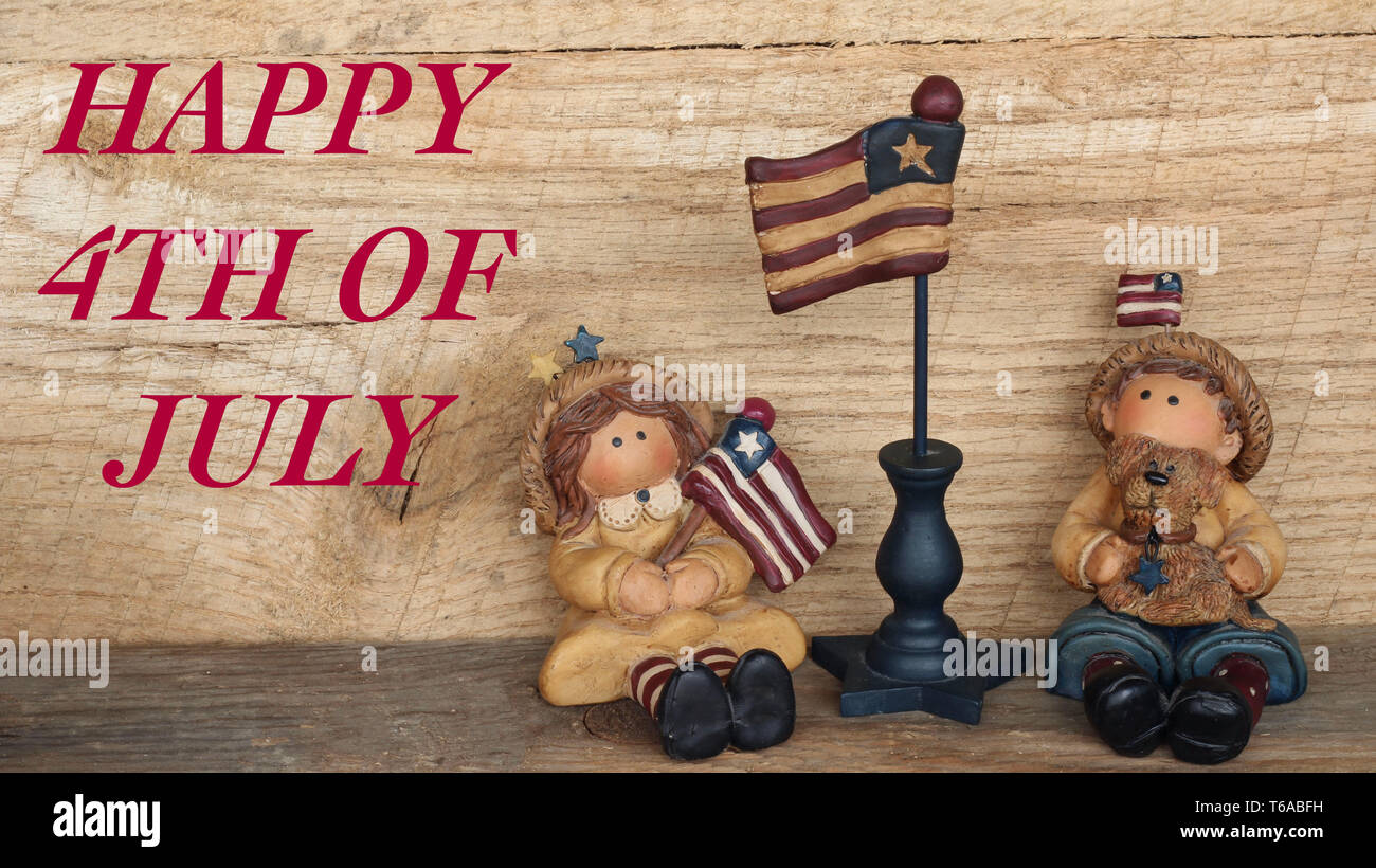 resin country boy and girl sitting holding american flag with happy 4th of July in red text on a rustic wood background Stock Photo