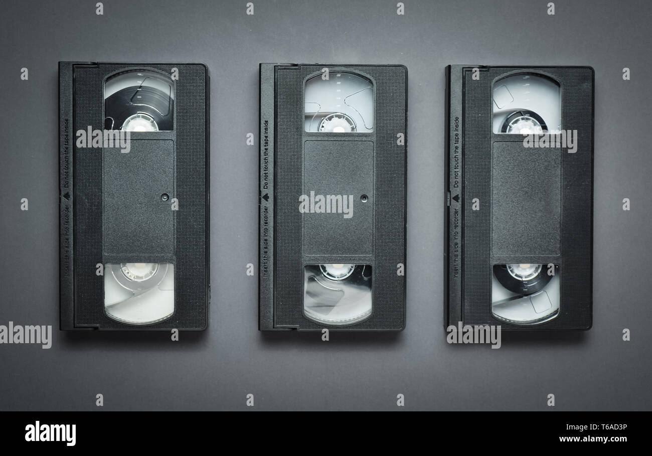Three video cassettes on a gray background. Retro technology from the 80s. Top view. Stock Photo