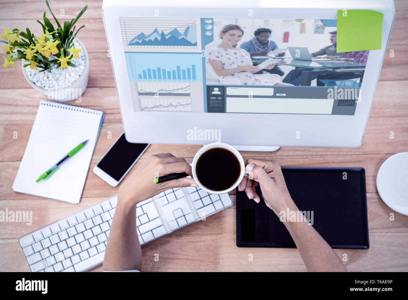 Composite image of editor holding tablet and smiling as team works behind her Stock Photo
