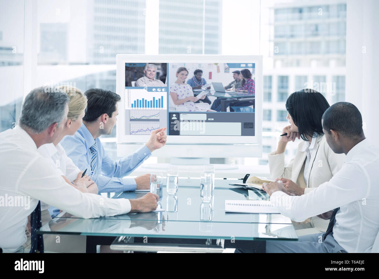 Composite image of editor holding tablet and smiling as team works behind her Stock Photo