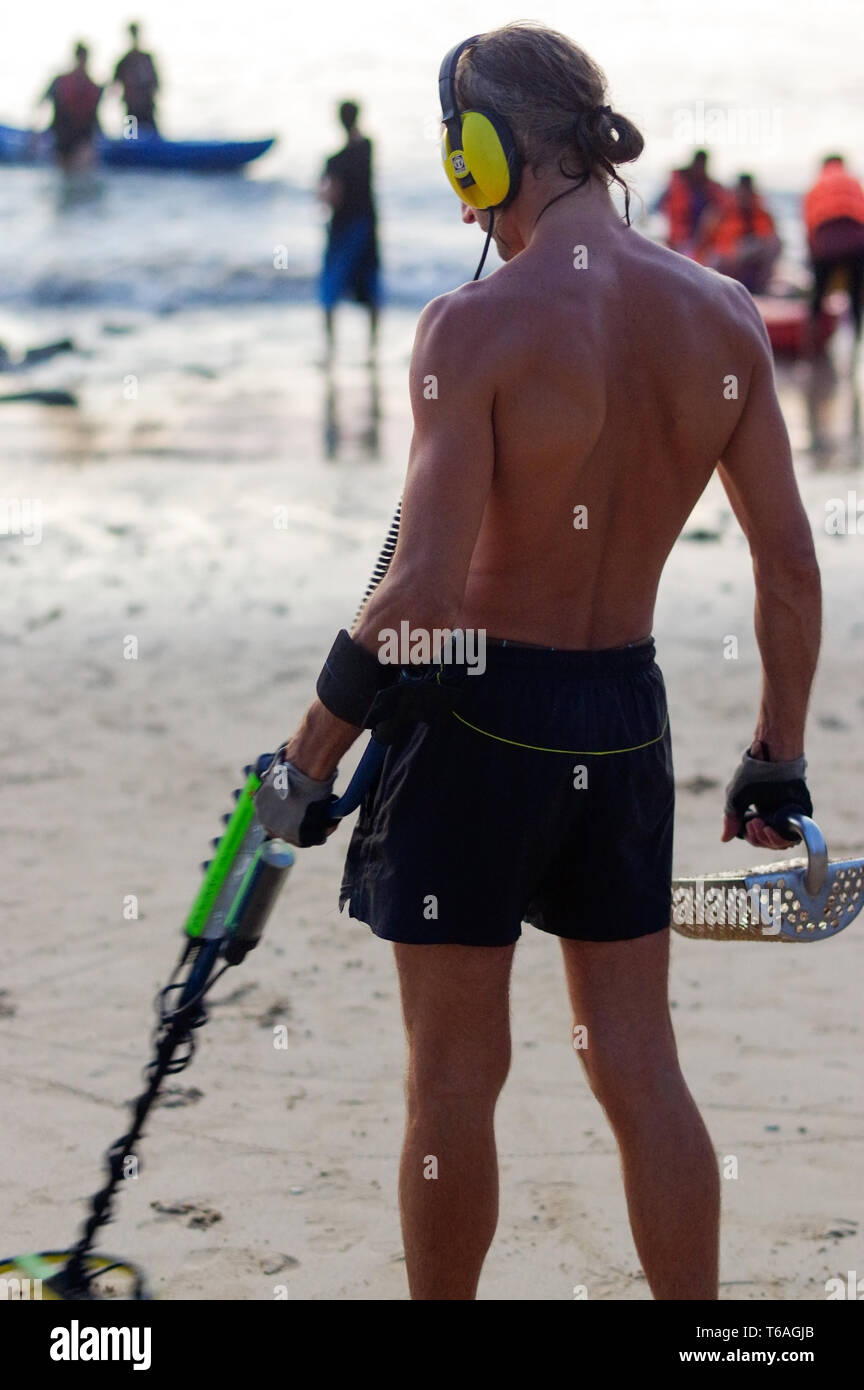 Treasure hunter with Metal detector on the beach Stock Photo