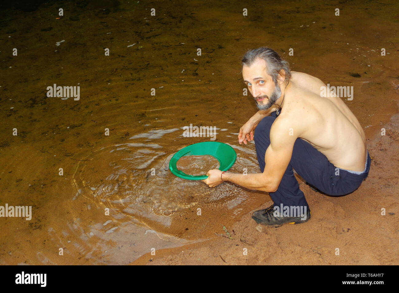 prospector panning gold in a river with sluice box Stock Photo
