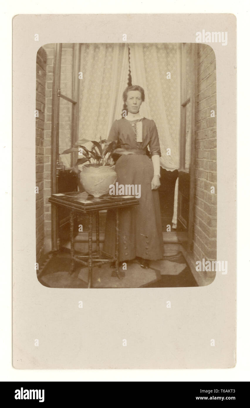 Edwardian postcard of woman outside house with Aspidistra house plant in pot, U.K. circa 1910 Stock Photo
