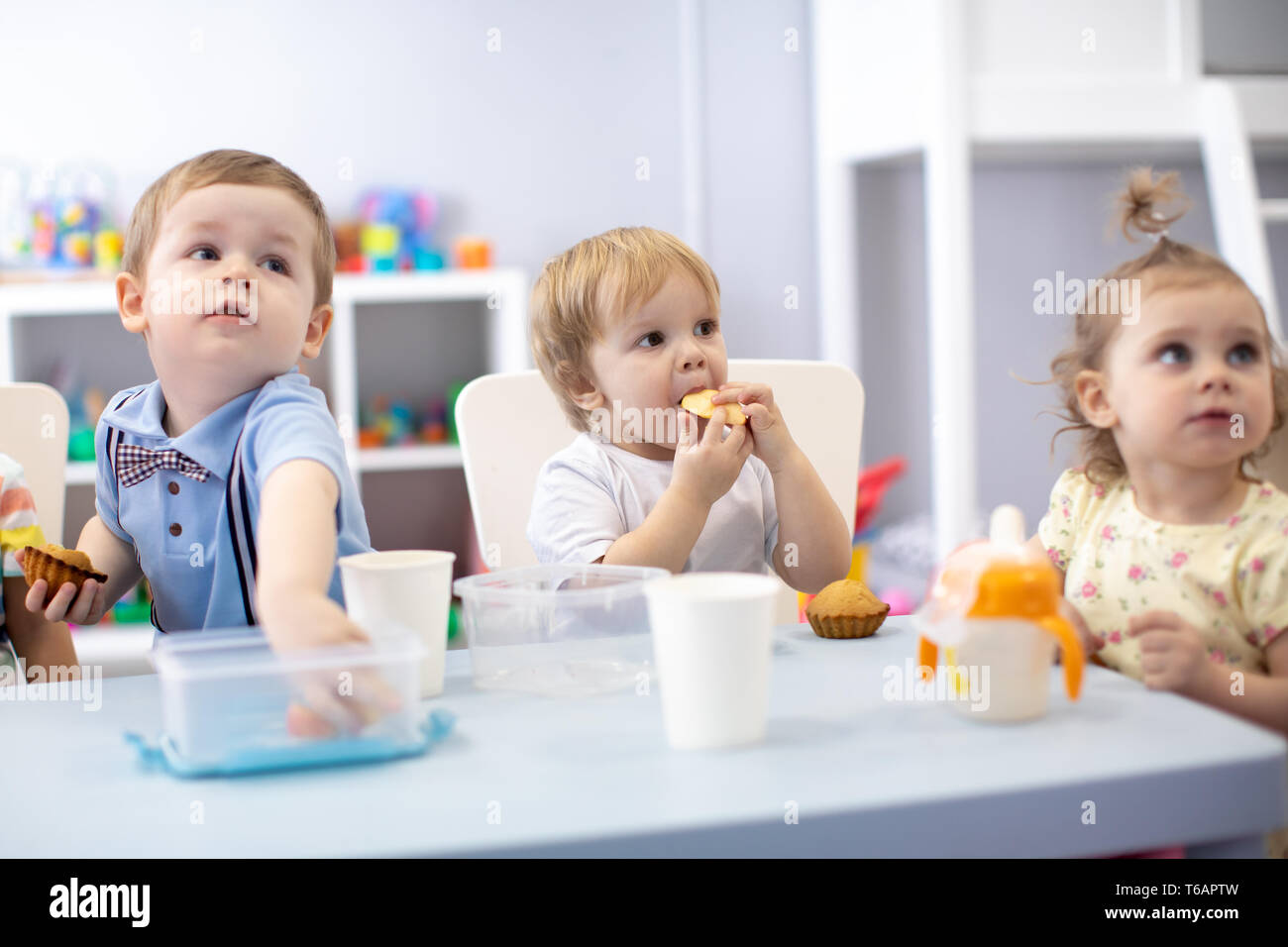 babies children toddlers have dinner in nursery or kindergarten Stock