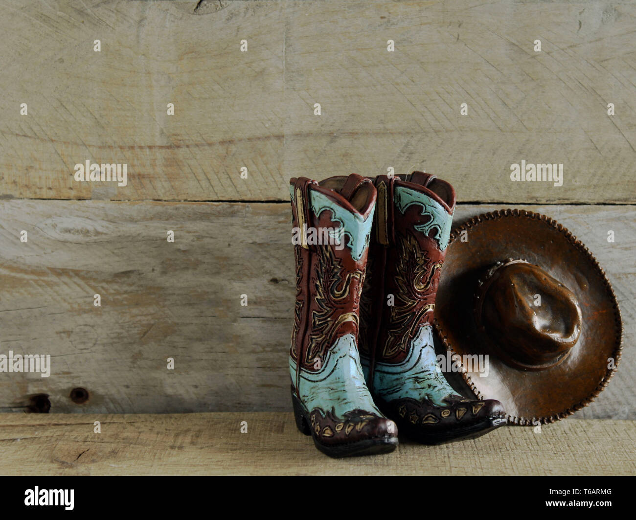 teal and brown cowboy boots and hat laying on a bed of leaves Stock Photo