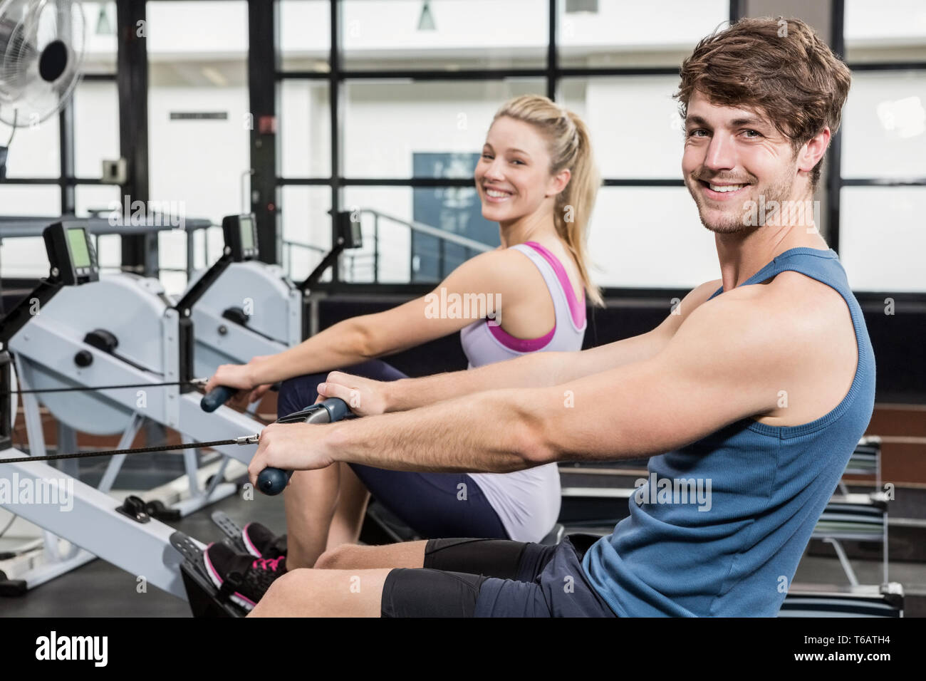 Portrait of a man and woman working out on rowing machine Stock Photo