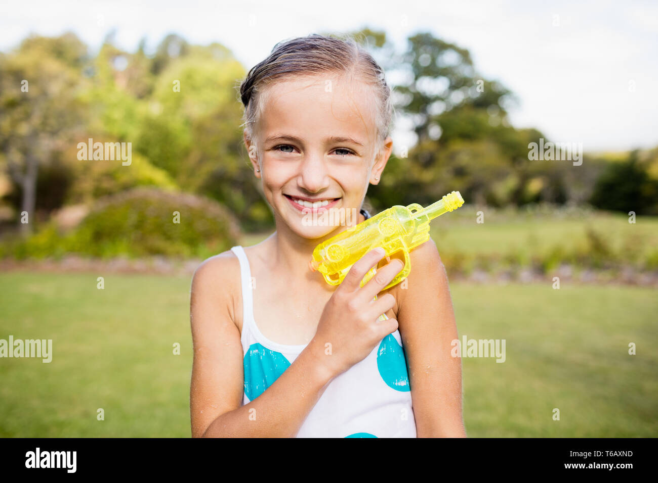 Kid posing at camera during a sunny day with her water gun Stock Photo