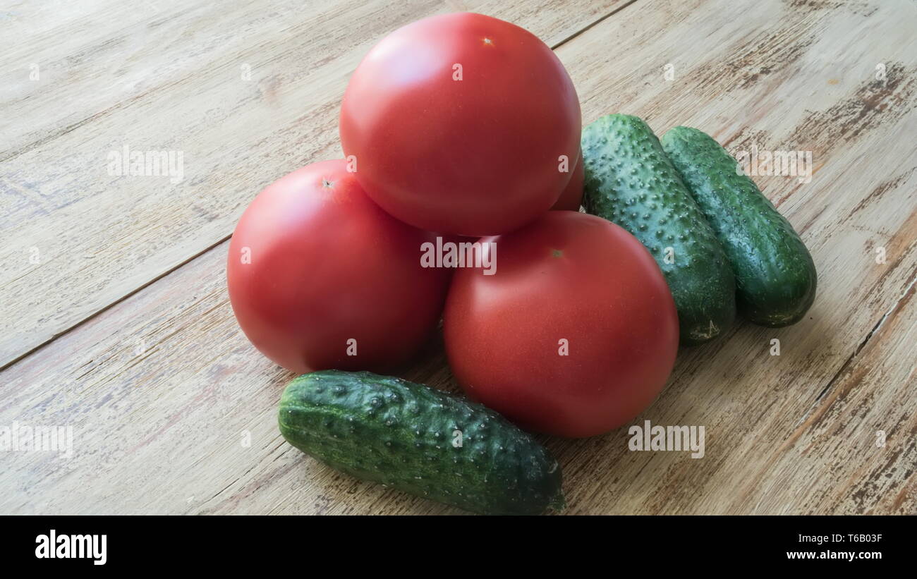 Green cucumbers and red tomatoes on wooden background Stock Photo