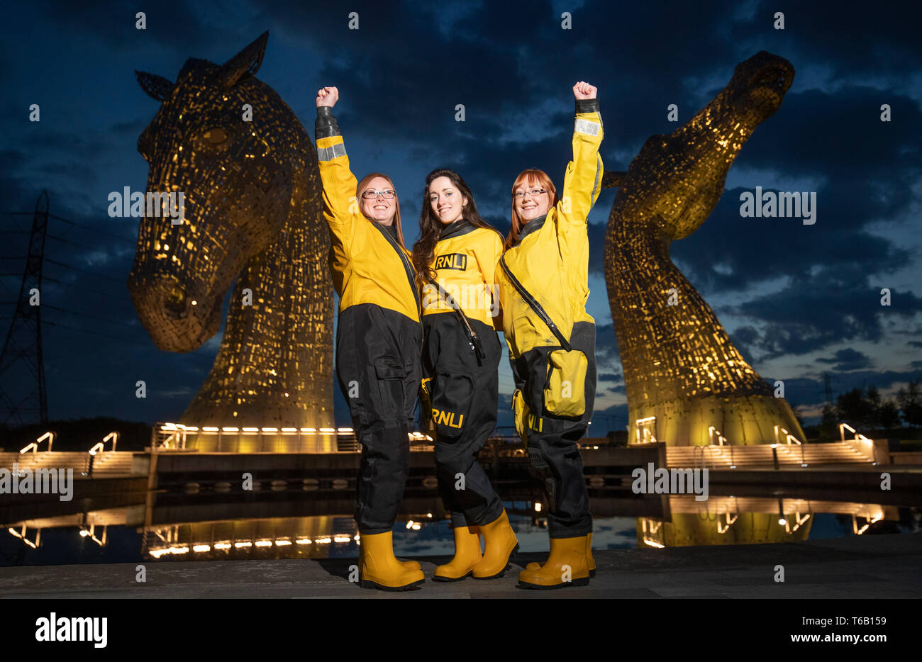 Members of the Queensferry crew (left to right) Adele Allan Arabella Kuszynska-Shields and Denise Tyler help launch the RNLI's 2019 Mayday campaign in front of The Kelpies, Falkirk, which is one of several landmarks across Scotland lit up yellow. Stock Photo
