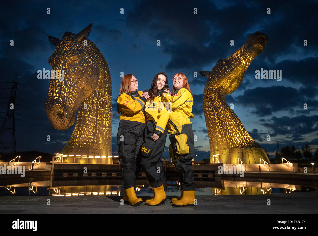 Members of the Queensferry crew (left to right) Adele Allan Arabella Kuszynska-Shields and Denise Tyler help launch the RNLI's 2019 Mayday campaign in front of The Kelpies, Falkirk, which is one of several landmarks across Scotland lit up yellow. Stock Photo