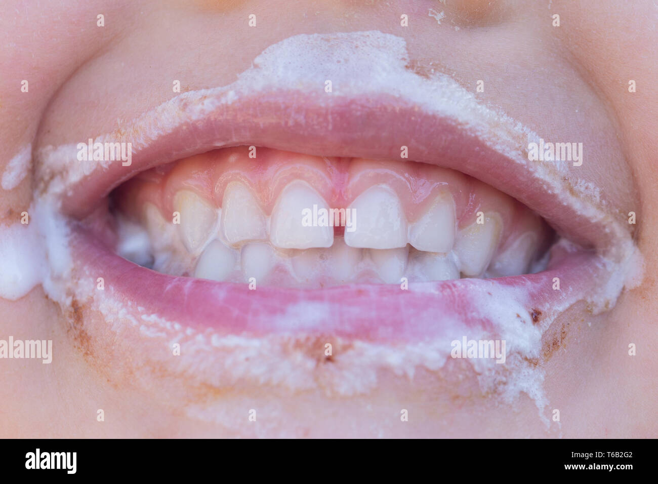 Closeup of young laughing girl eating ice cream with ice cream around her mouth Stock Photo