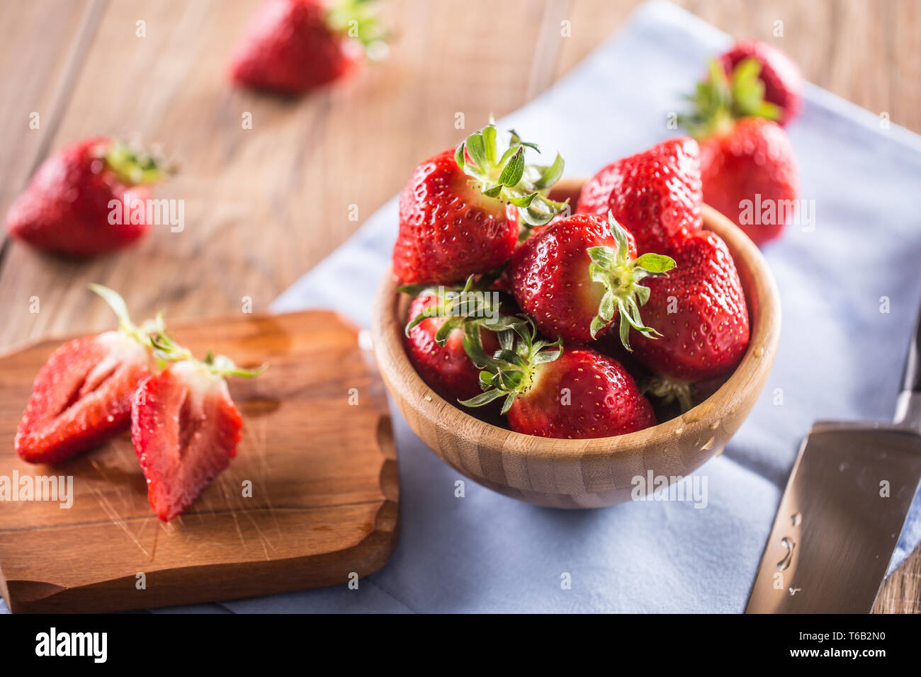 Juicy washed strawberries in wooden bowl on kitchen table Stock Photo