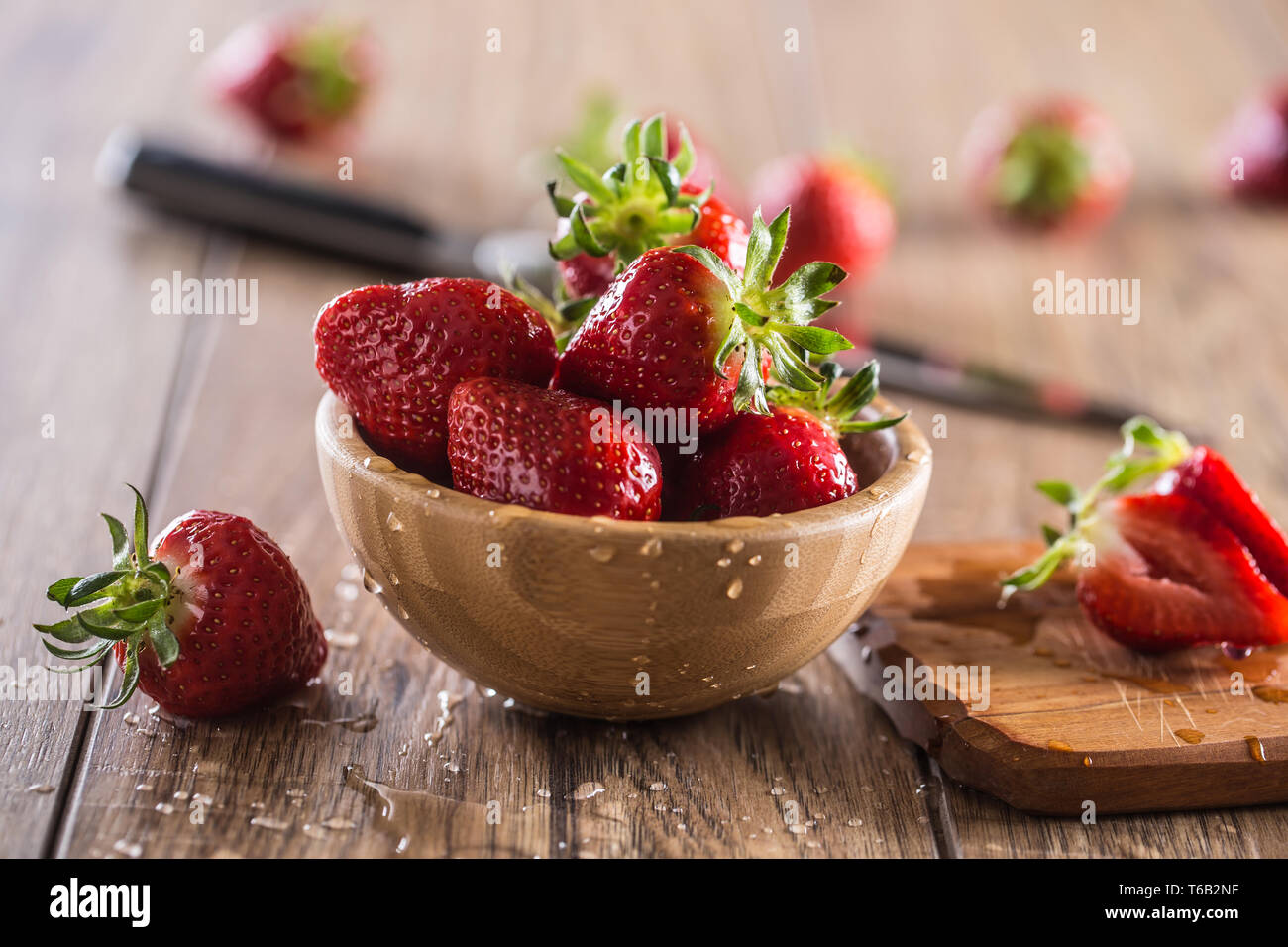 Juicy washed strawberries in wooden bowl on kitchen table Stock Photo