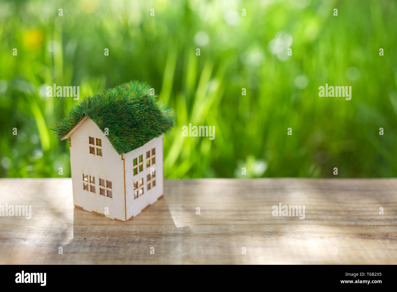 White model of house as symbol on green background Stock Photo