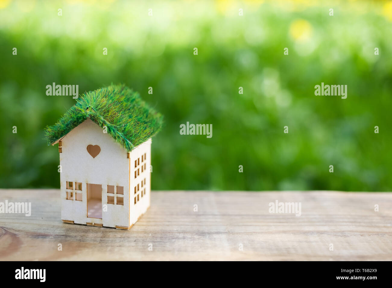 White model of house as symbol on green background Stock Photo - Alamy