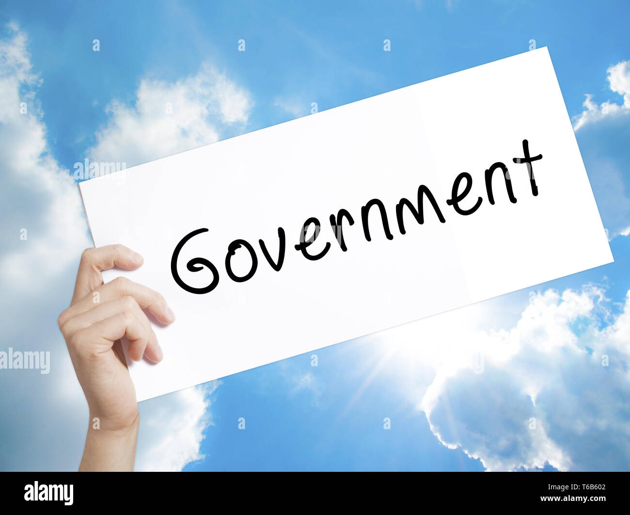Government Sign on white paper. Man Hand Holding Paper with text. Isolated on sky background Stock Photo
