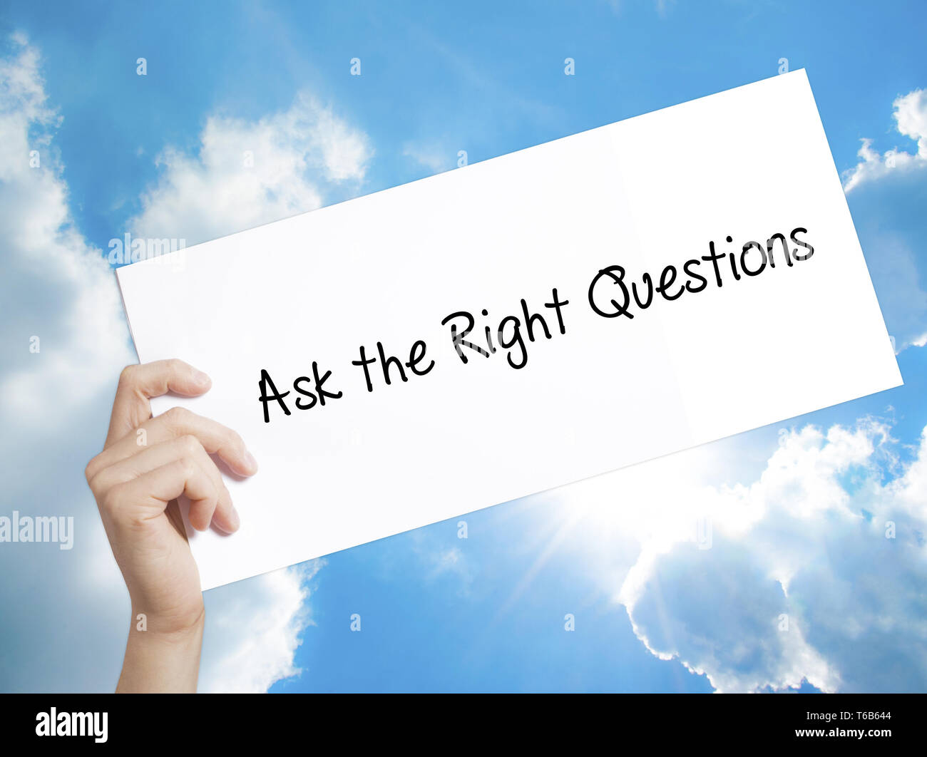 Ask the Right Questions Sign on white paper. Man Hand Holding Paper with text. Isolated on sky background Stock Photo