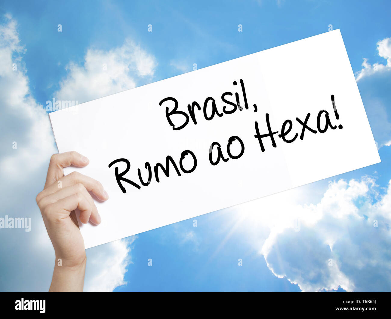 Brasil, Rumo ao Hexa! Sign on white paper. Man Hand Holding Paper with text. Isolated on sky background. Stock Photo