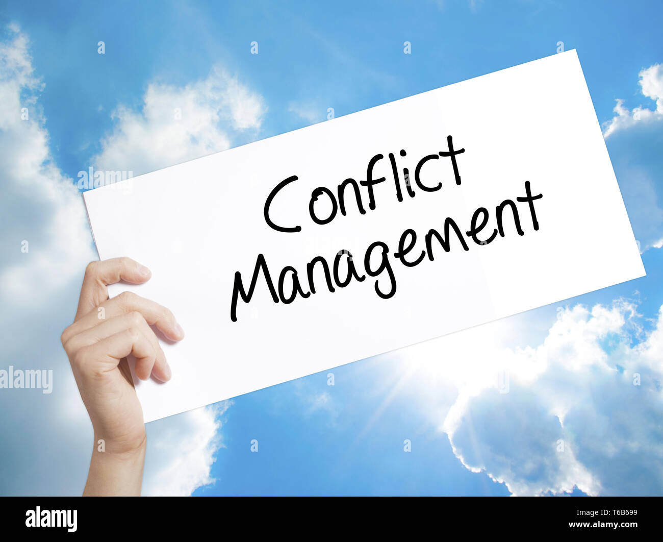 Conflict Management Sign on white paper. Man Hand Holding Paper with text. Isolated on sky background. Stock Photo