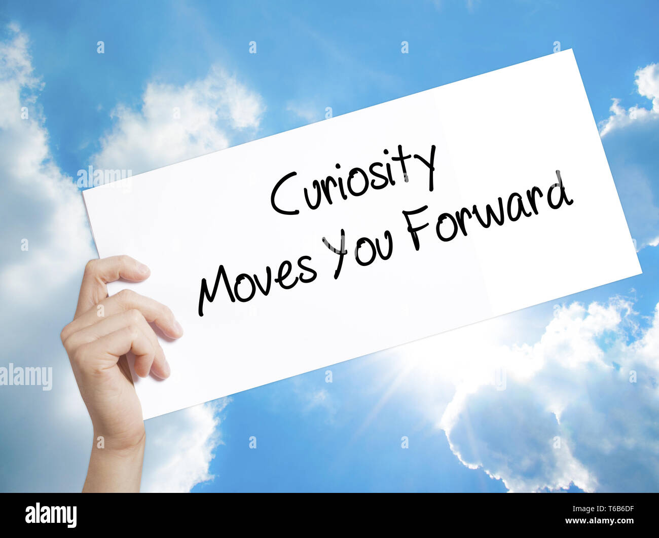 Curiosity Moves You Forward Sign on white paper. Man Hand Holding Paper with text. Isolated on sky background Stock Photo