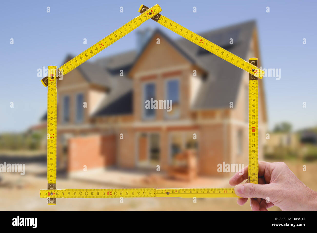 shell of house under construction with folding ruler in hand of real estate agent Stock Photo
