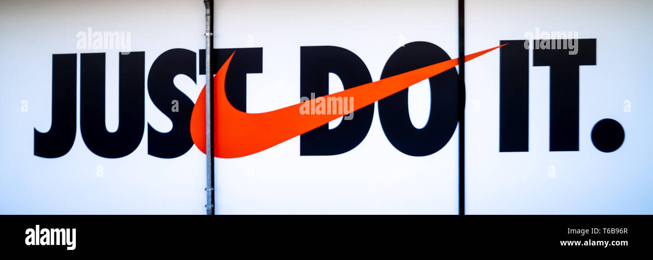The Nike logo and Nike motto 'just do it' on the window display in an outlet in Wolfsburg, Germany, April 20, 2019 Stock Photo