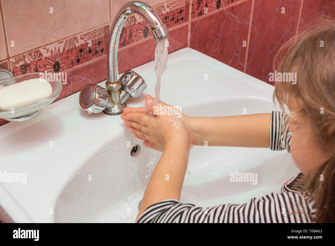 Five-year girl washing her hands in the sink Stock Photo