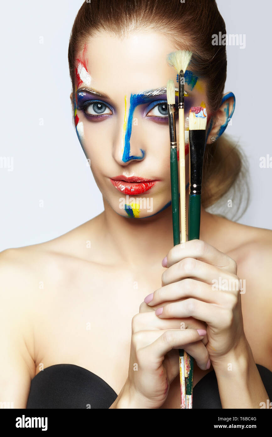 Young female painter with paint brush in hand and acrylic paint on face Stock Photo Alamy