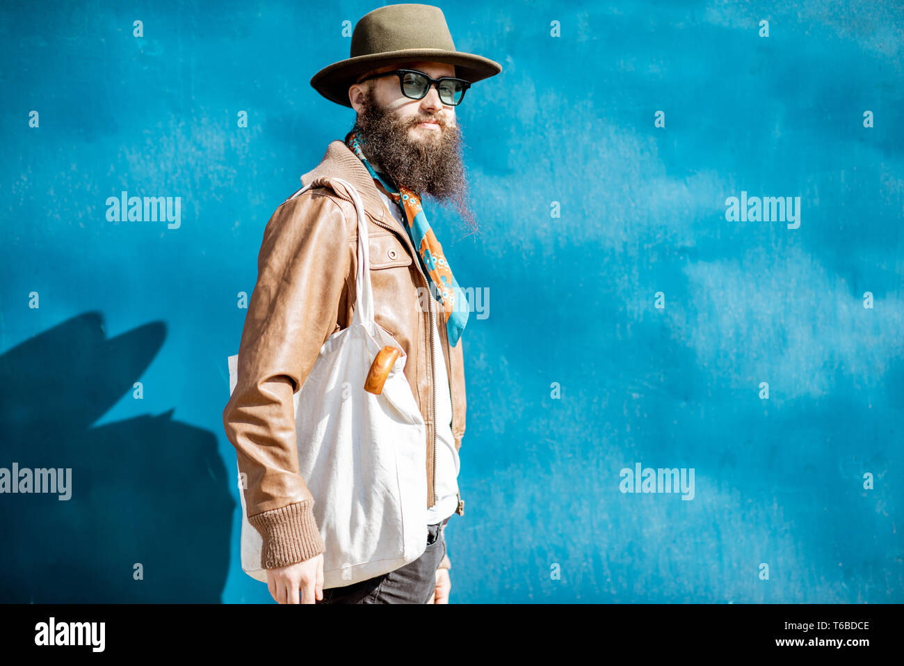 Portrait of a stylish bearded man dressed in jacket and hat standing ...