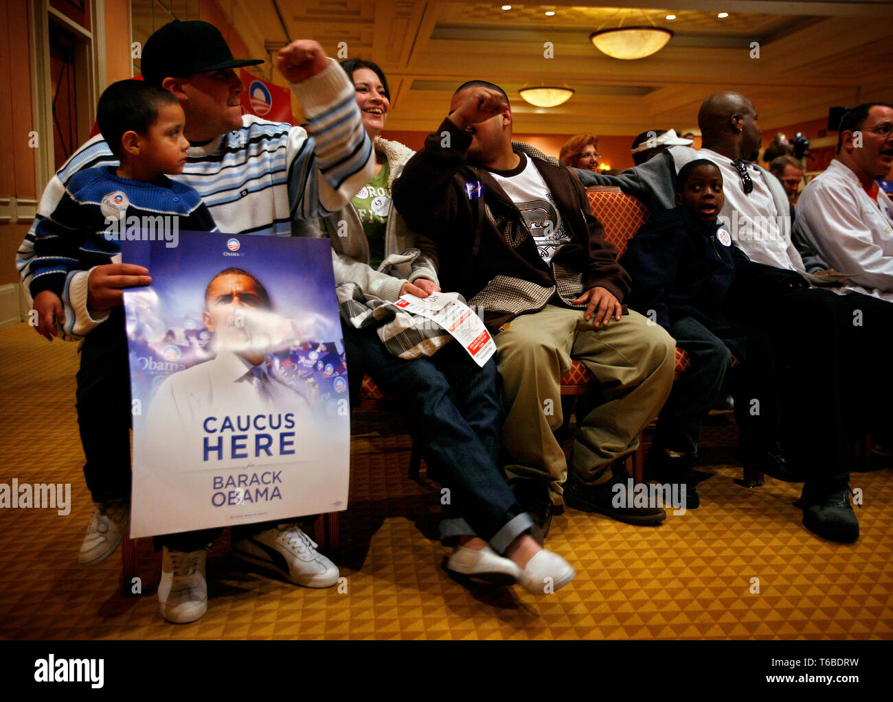 Employees at the Caesar Casino and Hotel attending caucus at their hotel.  Quincy Smith (7), next to his father Mark, is looking over to the Sanchez family (with the poster) as they are all supporting Obama at the Caucus. Stock Photo