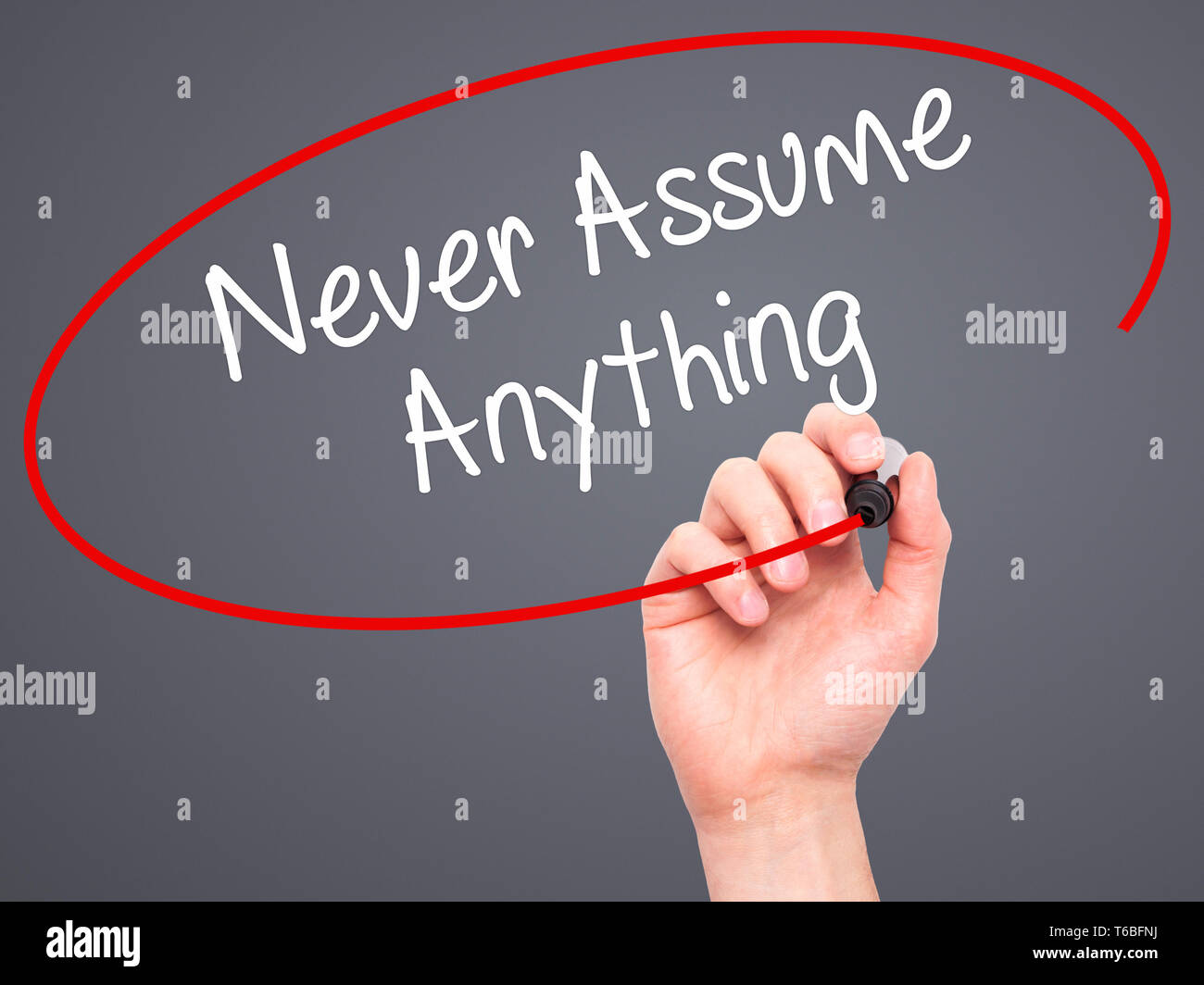 Man Hand writing Never Assume Anything with black marker on visual screen Stock Photo